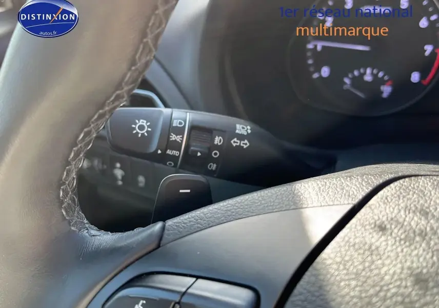 Gros plan sur le volant cuir multifonction et les commandes d'éclairage d'une Hyundai i30 gris argent 2024.