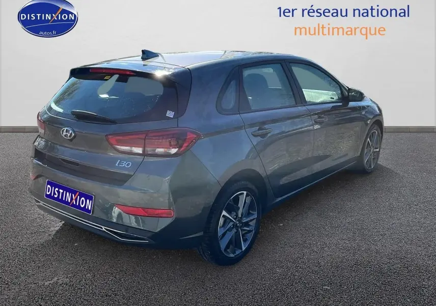 Hyundai i30 gris argent vue 3/4 arrière droit, avec jantes alliage et feux arrière LED distinctifs.