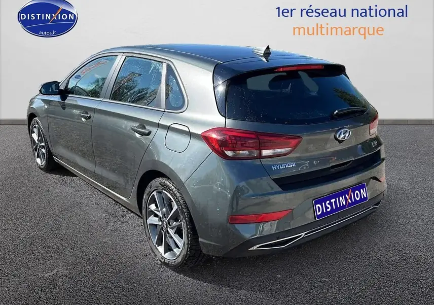 Vue 3/4 arrière droit d'une Hyundai i30 gris argent 2024 avec jantes alliage et vitres arrière surteintées.