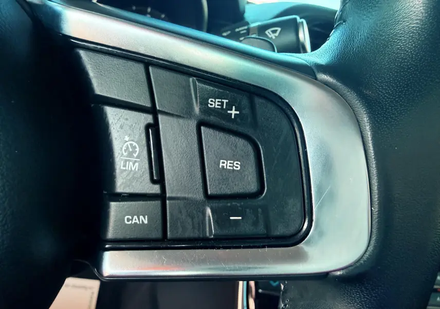 Gros plan sur les commandes de régulateur de vitesse au volant cuir noir d'une Jaguar XE 2019.