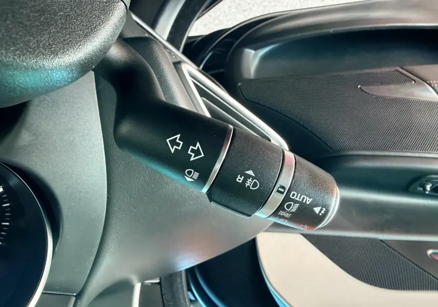 Le commodo des clignotants et phares dans l'habitacle noir d'une Jaguar XE 2019 vue côté gauche.