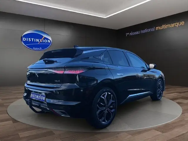 Vue 3/4 arrière droite d'une DS4 noire 2022 avec jantes noires bicolores, dans un showroom lumineux.