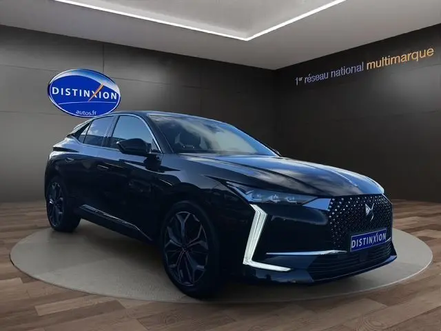 Vue 3/4 avant d'une DS4 noire 2022 avec calandre distinctive et jantes foncées dans un showroom.