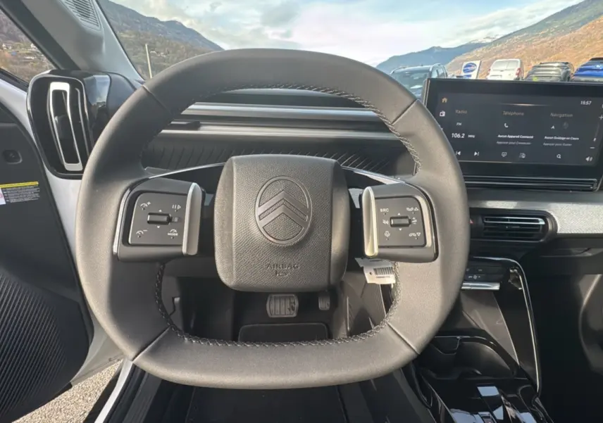 Vue intérieure centrée sur le volant cuir multifonctions du Citroën C3 Aircross blanc banquise avec écran tactile 10,25 pouces.