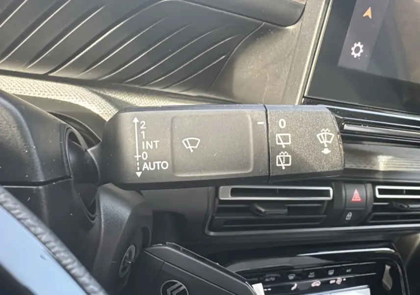 Gros plan sur la commande des essuie-glaces à gauche du volant dans l'habitacle du Citroën C3 Aircross blanc banquise.