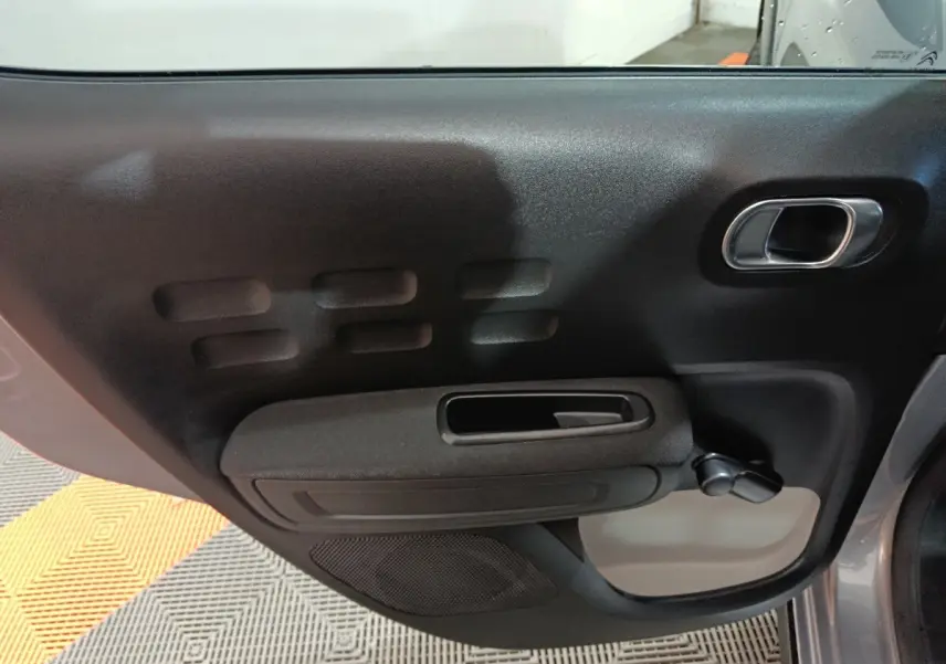 Vue rapprochée de la porte arrière droite gris foncé de la Citroën C3 avec poignée et manivelle de vitre manuelle.