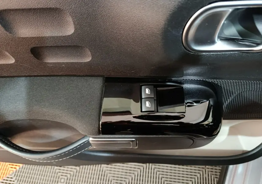 Détail des commandes de lève-vitres sur la porte côté conducteur d'une Citroën C3 gris foncé, finition intérieure noire.