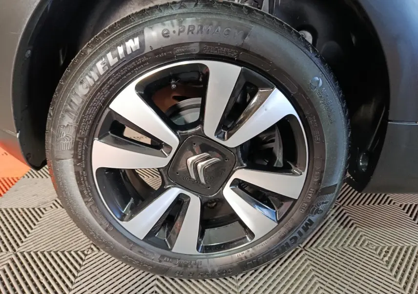 Gros plan sur la roue avant droite d'une Citroën C3 gris foncé, avec jante alliage bicolore et pneu Michelin.