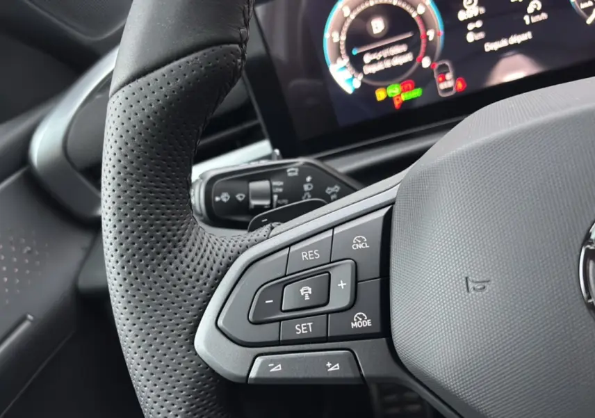 Gros plan sur le volant cuir noir perforé du Volkswagen T-Roc 2026 avec commandes multifonctions et tableau de bord digital.