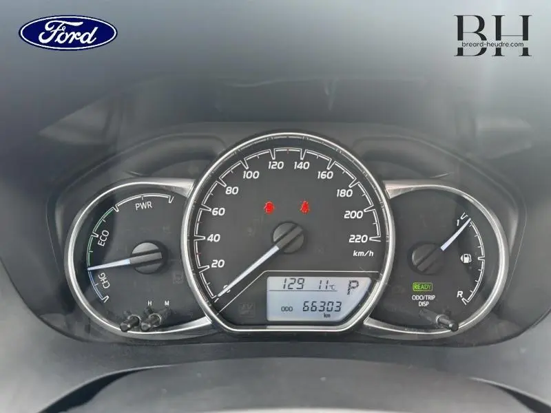 Tableau de bord de Toyota Yaris 116h blanc, affichage compteur vitesse, jauge essence et indicateurs hybrides.