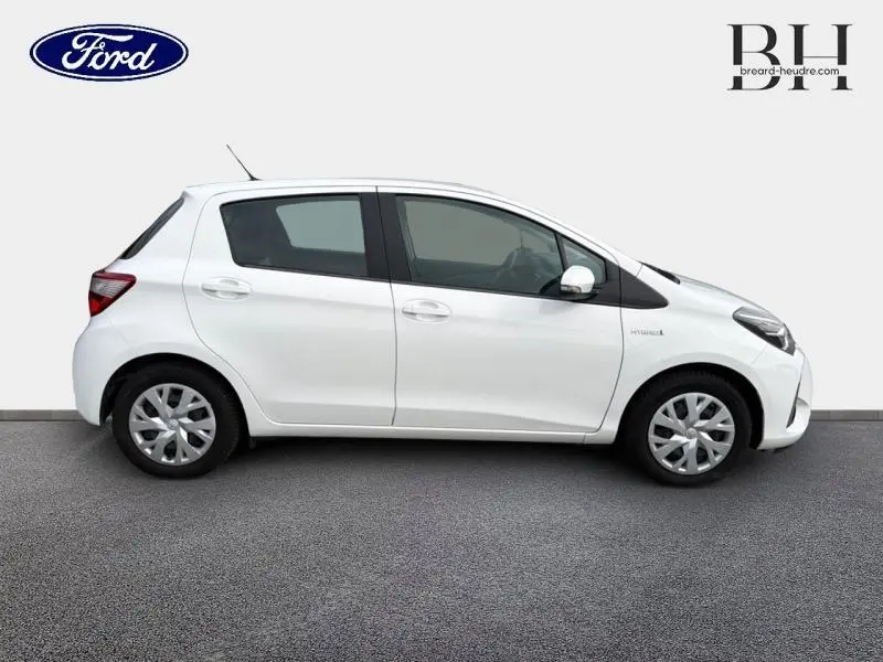 Profil droit d'une Toyota Yaris 116h France Business blanche, compacte avec enjoliveurs et vitres teintées.