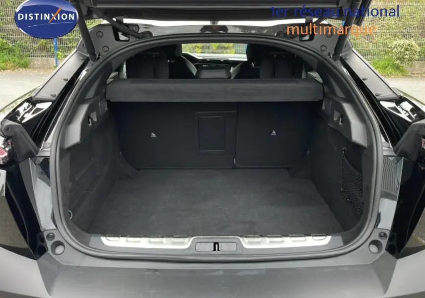 Coffre ouvert d’une Peugeot 408 Hybrid 145ch GT noir métal, vue arrière montrant l’espace de chargement vide.