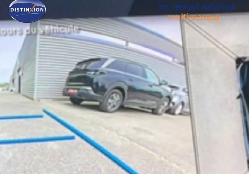 Peugeot 408 Hybrid 145ch noir métal vue 3/4 arrière droit sur parking extérieur près d’un bâtiment industriel.
