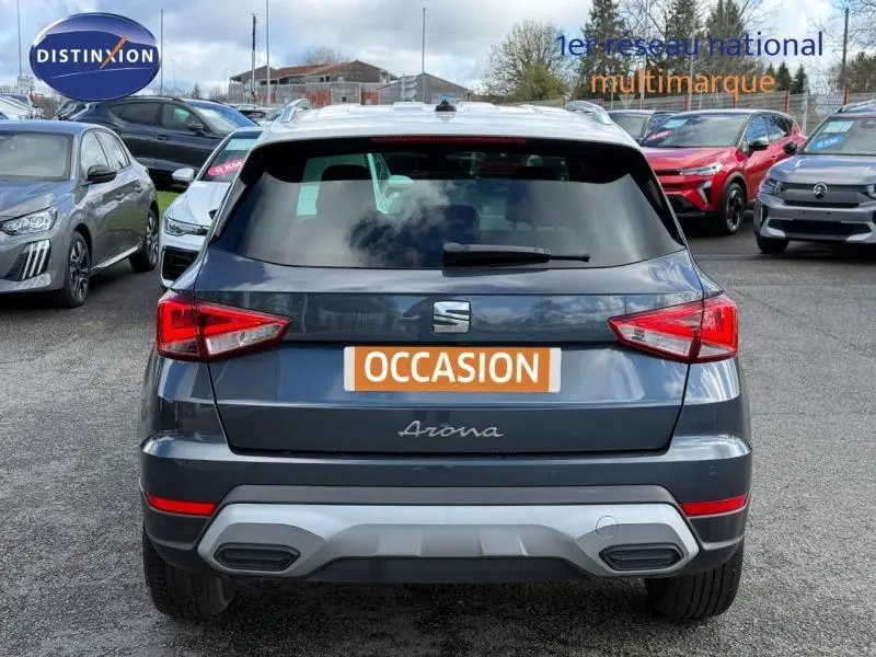 Vue arrière d'un SEAT Arona 2025 bleu saphir métal avec toit blanc, immatriculé occasion sur parking multimarque.