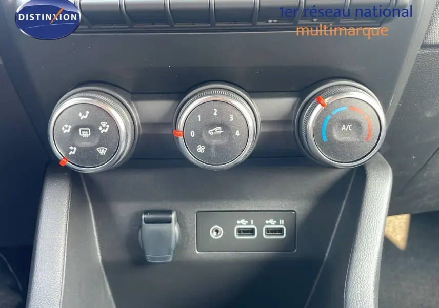 Commandes de climatisation avec trois boutons rotatifs et deux ports USB sur la console centrale d'une Renault Clio noire étoile métal.