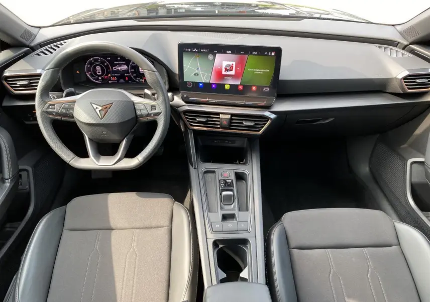 Intérieur de la CUPRA LEON ST 2024 noir Midnight, vue frontale du poste de conduite avec écran tactile et volant multifonction.