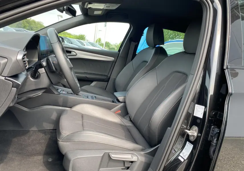 Intérieur côté conducteur de la CUPRA LEON ST 2024 noir Midnight avec sièges avant en cuir et tableau de bord moderne.