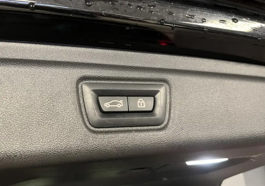 Boutons d'ouverture et de verrouillage du coffre sur la partie intérieure du hayon noir d'une BMW Série 3 Touring.