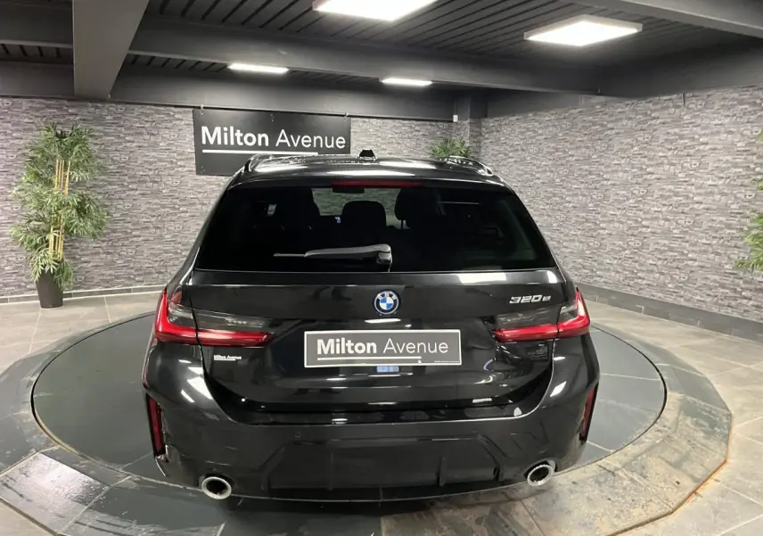 Vue arrière d'une BMW Série 3 320e Touring noire avec double sortie d'échappement et feux LED distinctifs.