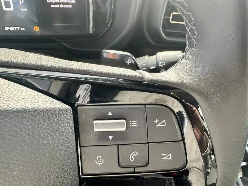 Gros plan sur les commandes vocales et téléphone au volant cuir du Citroën Berlingo gris Artense 2024 côté gauche.