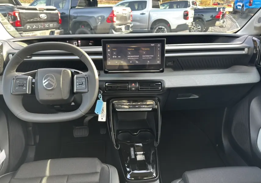 Vue intérieure du tableau de bord et volant cuir multifonctions du Citroën C3 Aircross Hybrid 145 noir Perla Nera 2025.