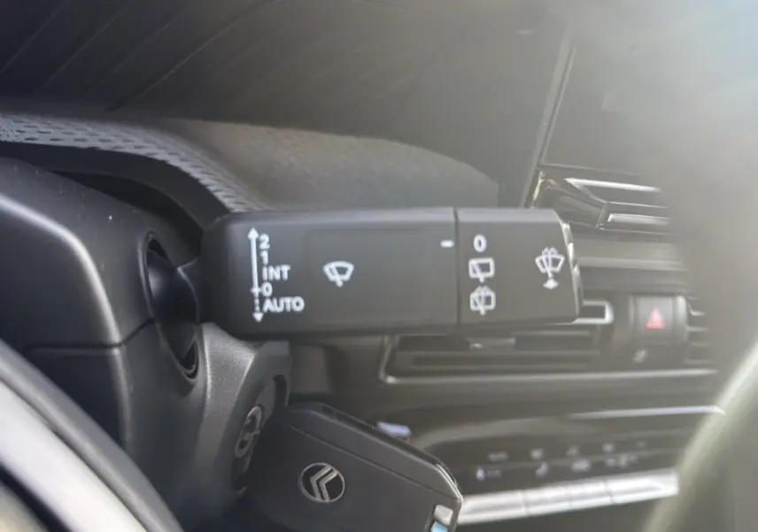 Gros plan sur la commande d’essuie-glace du Citroën C3 Aircross noir perla nera, intérieur lumineux et moderne.