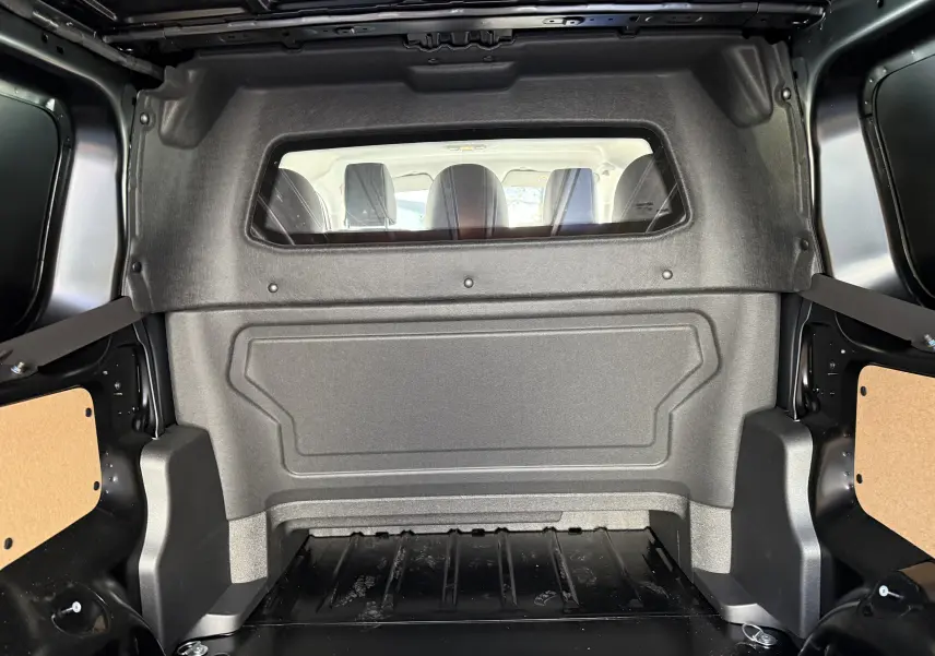 Intérieur de la cabine approfondie noire du Citroën Jumpy XL 2025, vue du compartiment de chargement vers les sièges arrière.