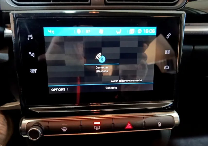 Gros plan sur l'écran tactile central noir de la Citroën C3 blanche, affichant la connexion Bluetooth téléphone.
