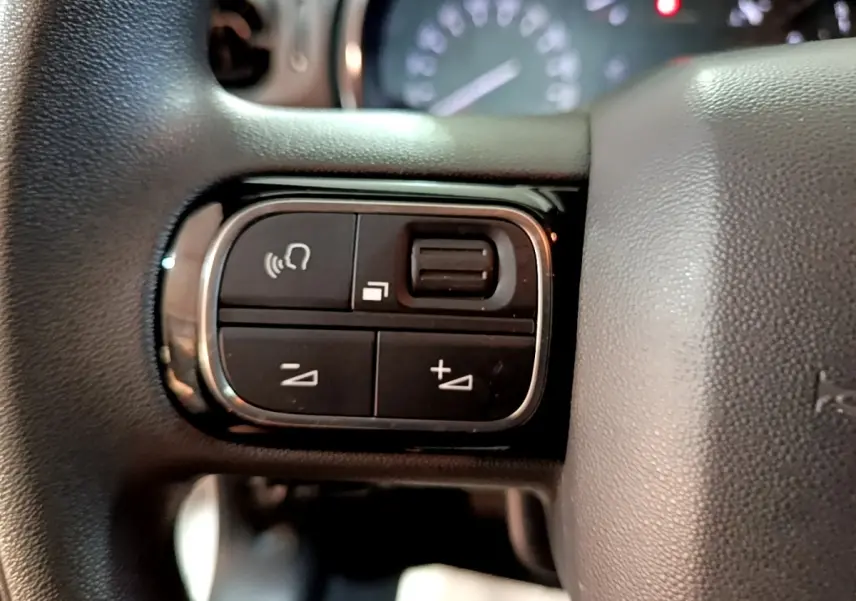 Gros plan sur les commandes vocales et volume au volant d'une Citroën C3 blanche, version Feel Business 2020.