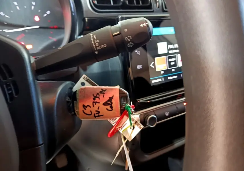 Vue rapprochée du volant et du commodo de la Citroën C3 blanche, avec l'écran tactile du tableau de bord en arrière-plan.