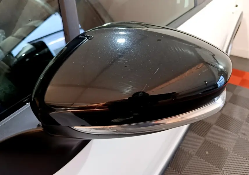 Gros plan sur le rétroviseur noir côté conducteur d'une Citroën C3 blanche vue de profil gauche.