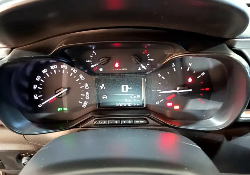 Vue rapprochée du tableau de bord numérique de la Citroën C3 blanche, affichant la vitesse à zéro et divers voyants allumés.