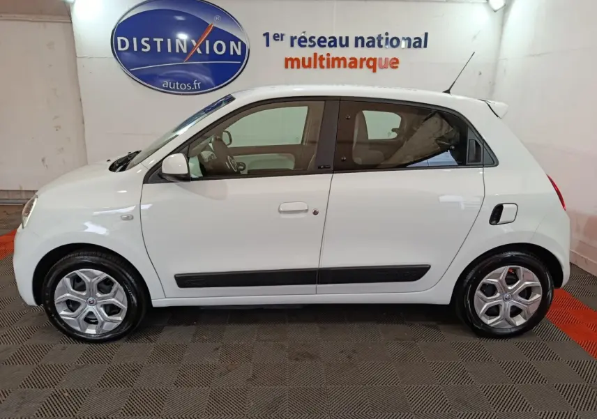 Profil latéral droit d'une Renault Twingo Zen blanche de 2021 avec poignées et rétroviseurs assortis, en intérieur showroom.