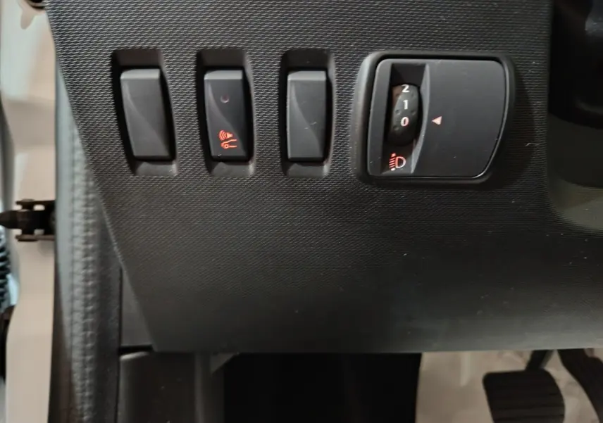 Détail des commandes d'éclairage et d'alerte sonore sur le tableau de bord côté gauche d'une Renault Twingo Zen blanche.
