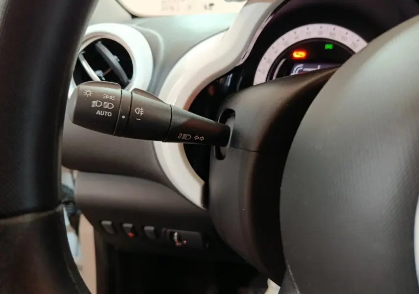 Gros plan sur la commande des phares et clignotants à gauche du volant dans l’habitacle blanc de la Renault Twingo Zen électrique 2021.