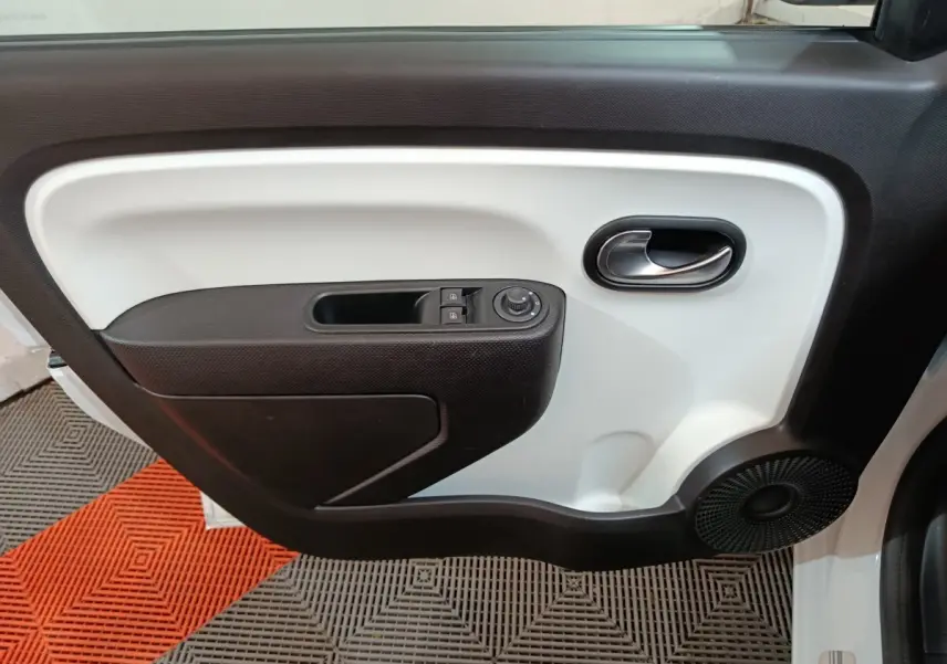 Vue intérieure du panneau de porte avant gauche de la Renault Twingo Zen blanc, avec commandes électriques et haut-parleur intégré.