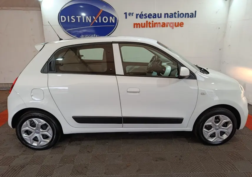 Profil droit d'une Renault Twingo Zen blanche de 2021, compacte avec poignées et bas de porte noirs, roues alliage.