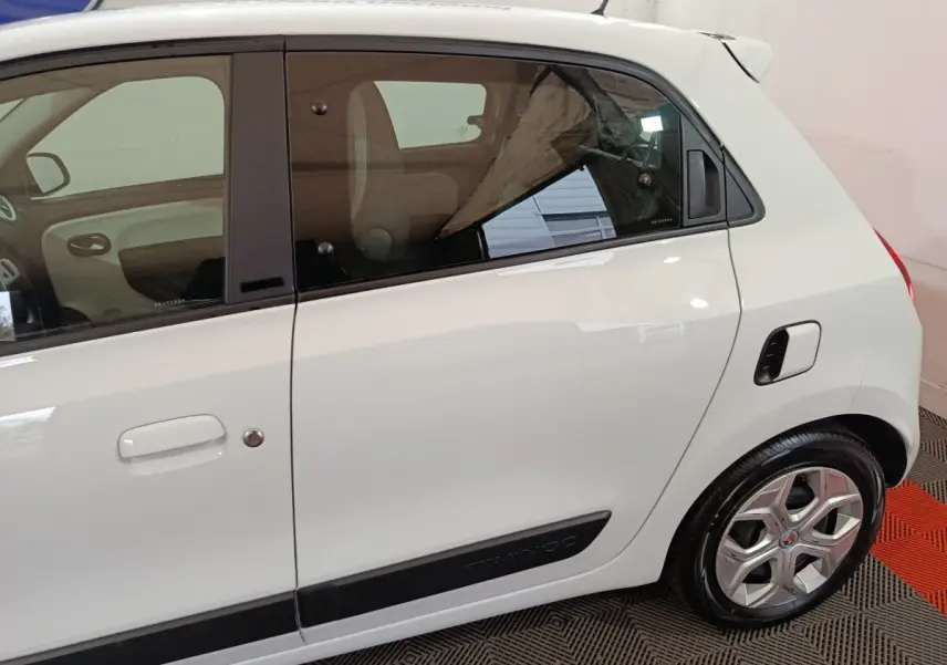 Vue latérale droite d'une Renault Twingo Zen blanche avec poignées de porte intégrées et logo Twingo sur bas de caisse noir.