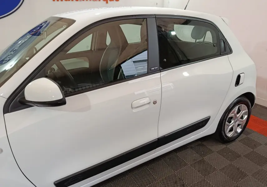 Profil droit d'une Renault Twingo Zen blanche électrique, avec poignées intégrées et jantes alliage visibles.