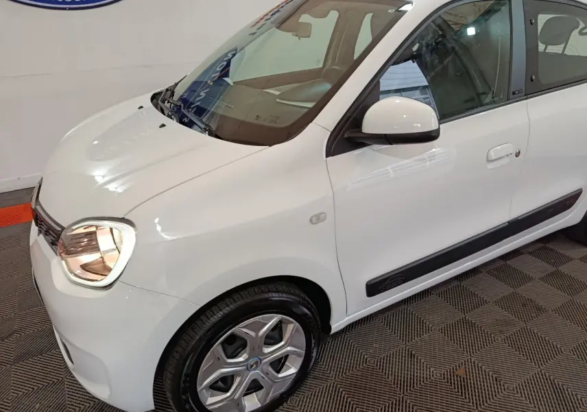 Renault Twingo Zen électrique blanche vue 3/4 avant droit, avec jantes spécifiques et rétroviseur blanc.