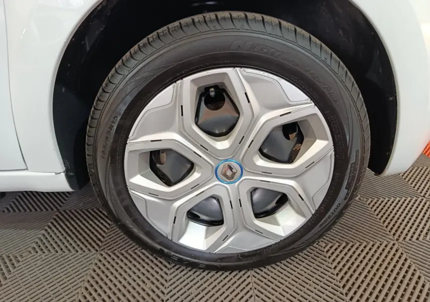 Vue rapprochée de la roue arrière droite d'une Renault Twingo Zen blanche de 2021, sur sol texturé.