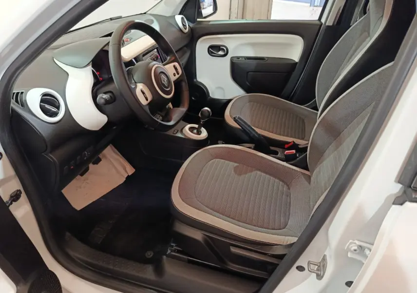 Vue intérieure côté conducteur de la Renault Twingo Zen blanche, avec tableau de bord et sièges gris en tissu.