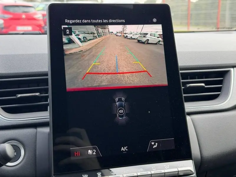Vue intérieure sur l'écran de recul du Renault Captur rouge, affichant les lignes d'aide au stationnement.