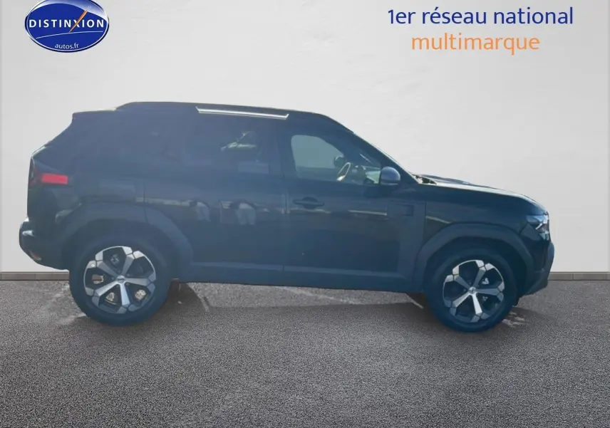Vue de profil côté gauche d'un Dacia Duster noir 2026 avec jantes alliage et barres de toit visibles.