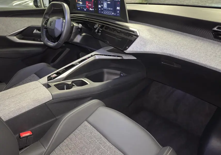 Intérieur avant droit du Peugeot 3008 2025 hybride avec tableau de bord tissu gris et double écran HD flottant.