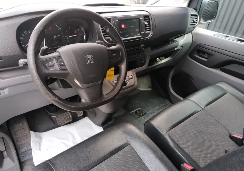 Vue intérieure côté conducteur du Peugeot Expert Fourgon 2020, tableau de bord avec écran tactile et sièges en tissu noir.