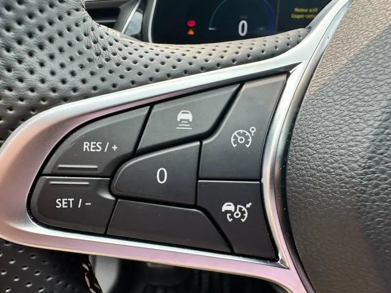 Gros plan sur les commandes noires du régulateur de vitesse au volant perforé du Renault Arkana noir métal 2023.