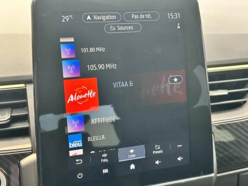 Écran tactile central du tableau de bord du Renault Arkana noir métal, affichant les stations radio et la navigation.