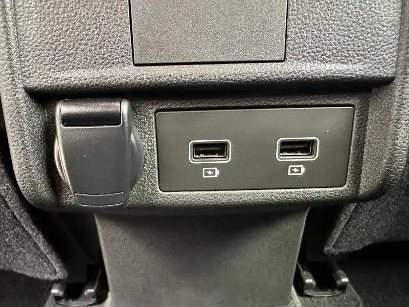 Gros plan sur deux ports USB et une prise 12V noirs intégrés dans la console arrière du Renault Arkana noir métal 2023.