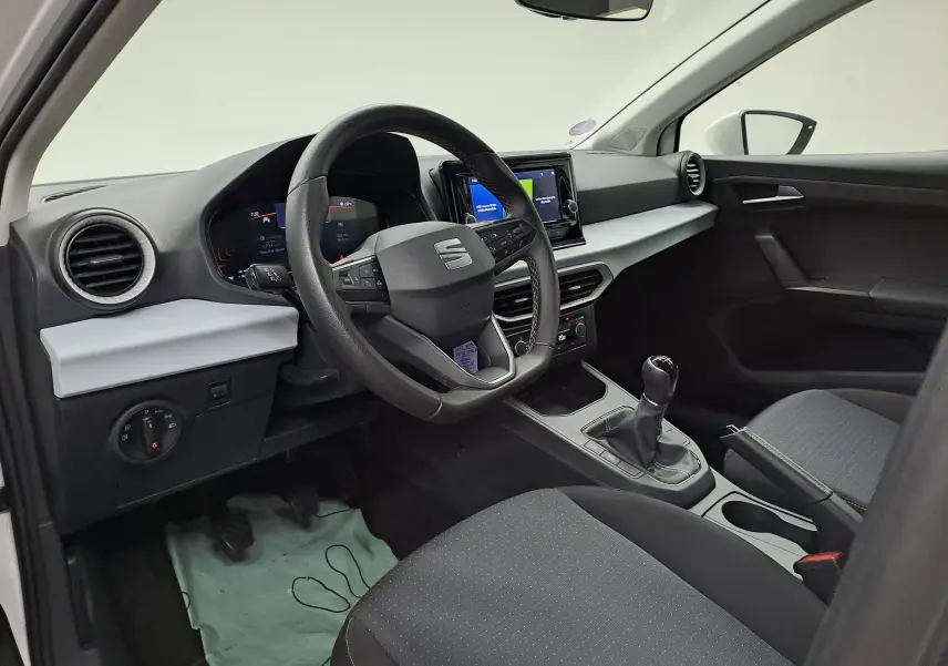 Intérieur côté conducteur de la SEAT Ibiza 2023 blanc candy, volant multifonction et boîte manuelle visible.